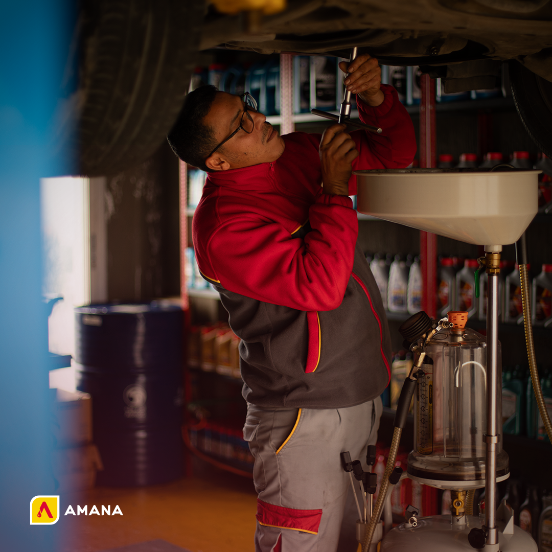 Image showing an Amana Petroleum Company's employee performing an oil change for a car, highlighting our professional automotive maintenance services.